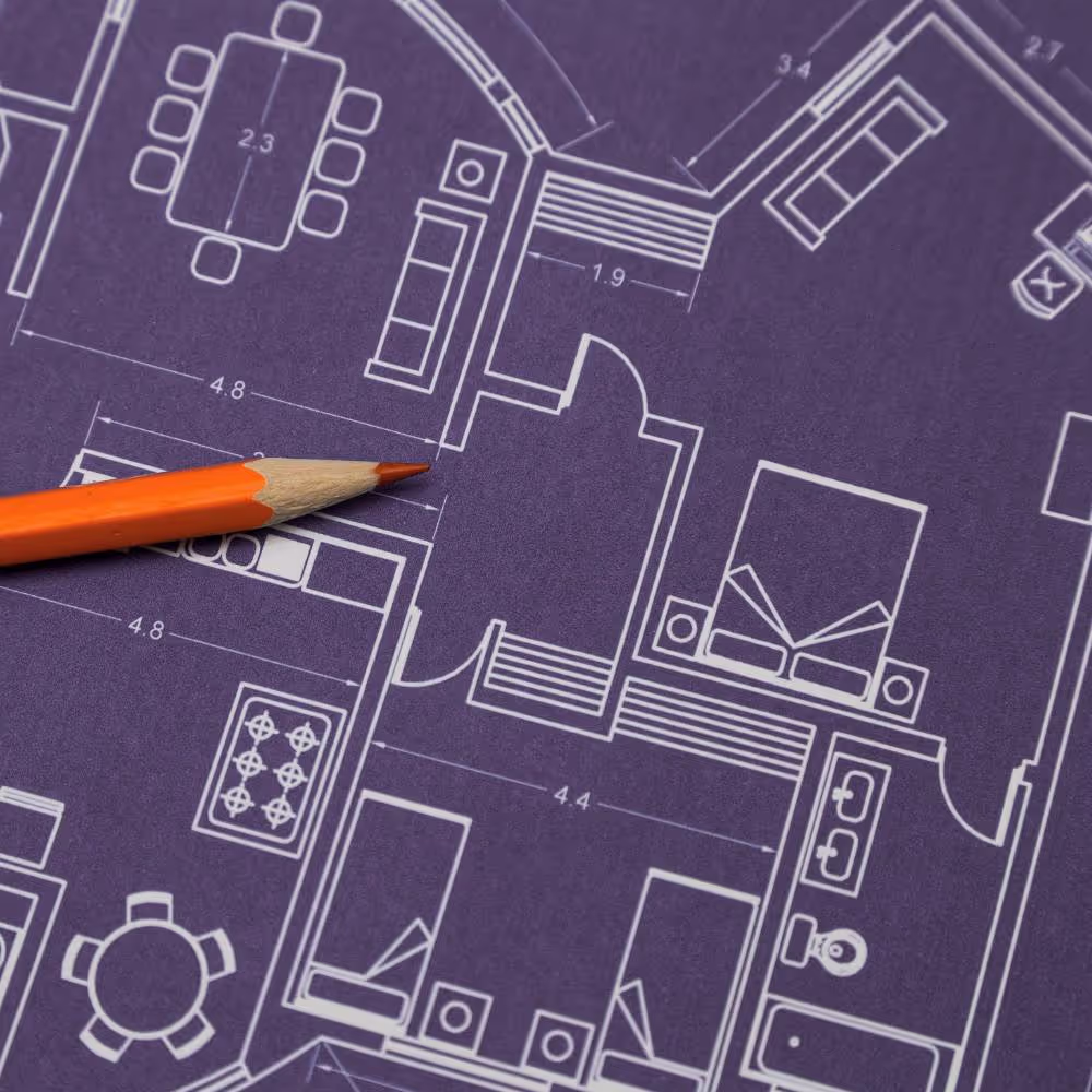 blueprints with orange pencil showing that Marketing is like architecture - planning is key